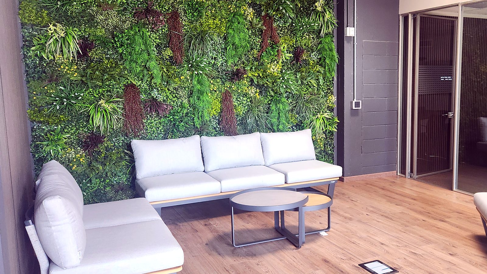 Area relax con parete verde e divano nella sede Media Solution a Caronno Pertusella